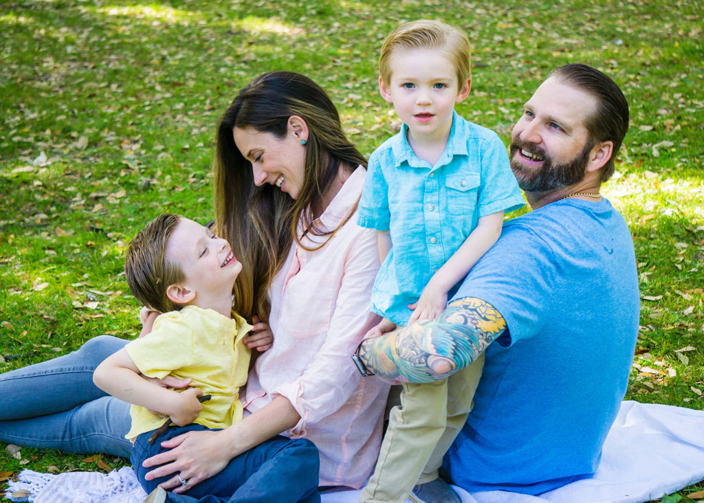 family of four sitting in Forsyth park for family photos