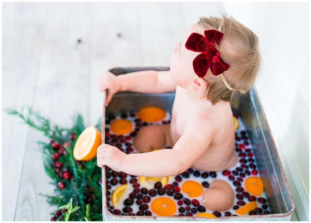 baby in an orange and cranberry milk bath