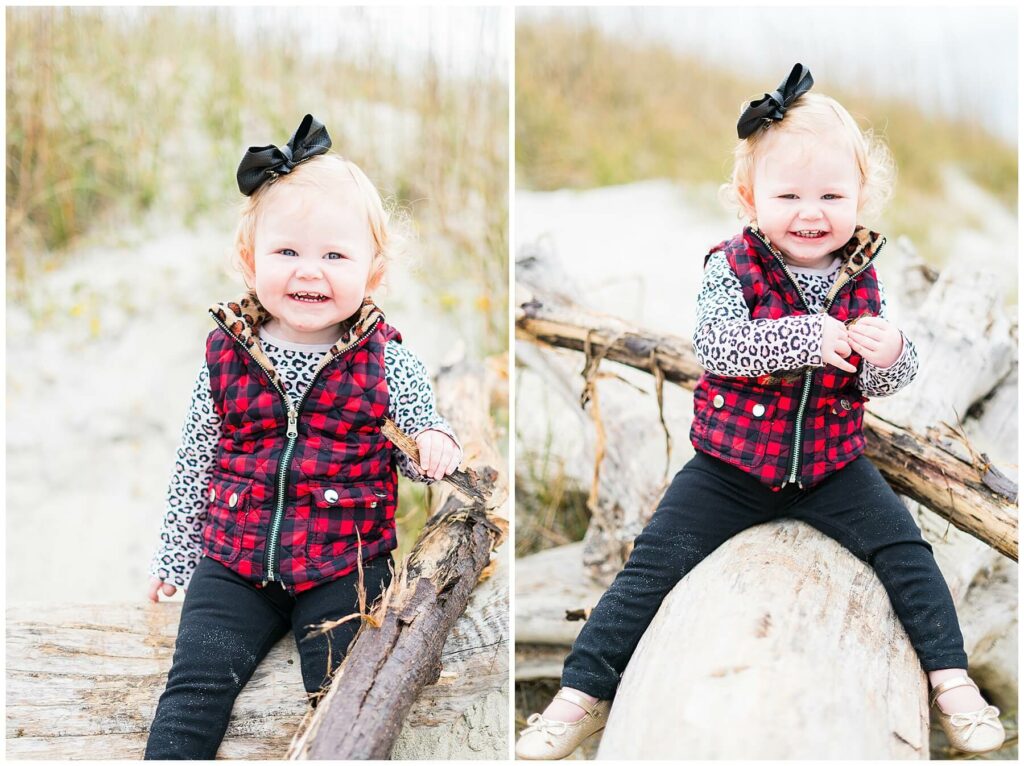 little girl in plaid vest sitting on driftwood