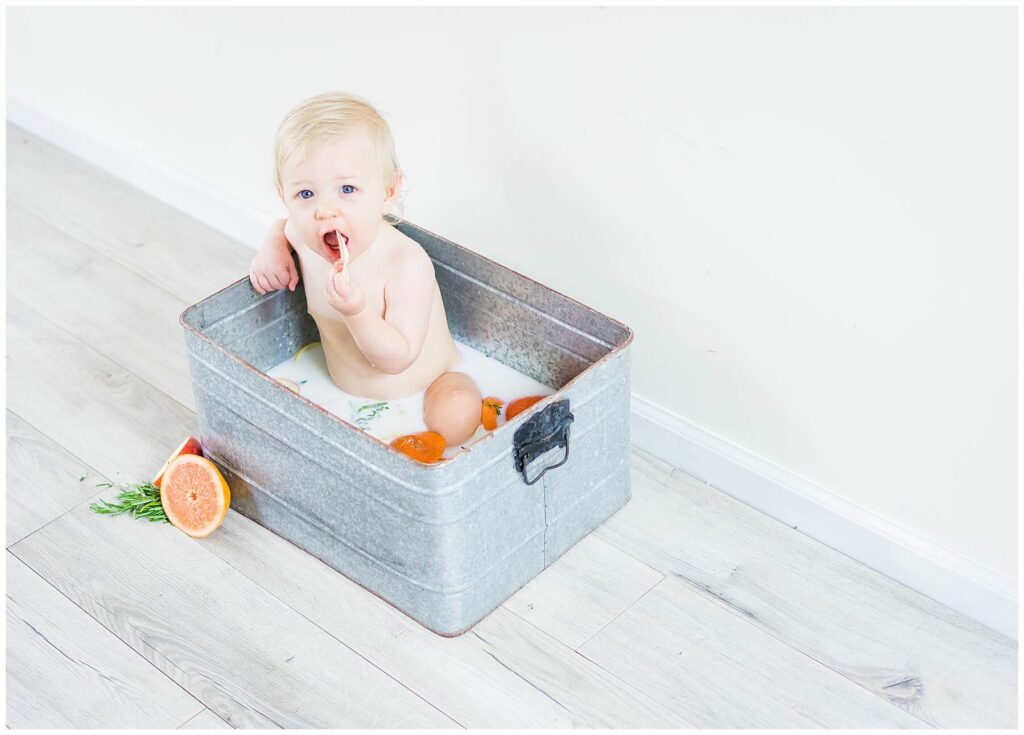 baby eating an orange in a milk bath