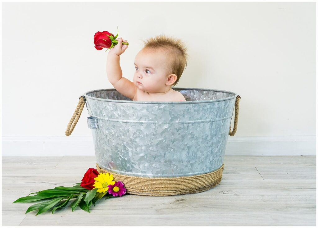 baby in milk bath holding a rose