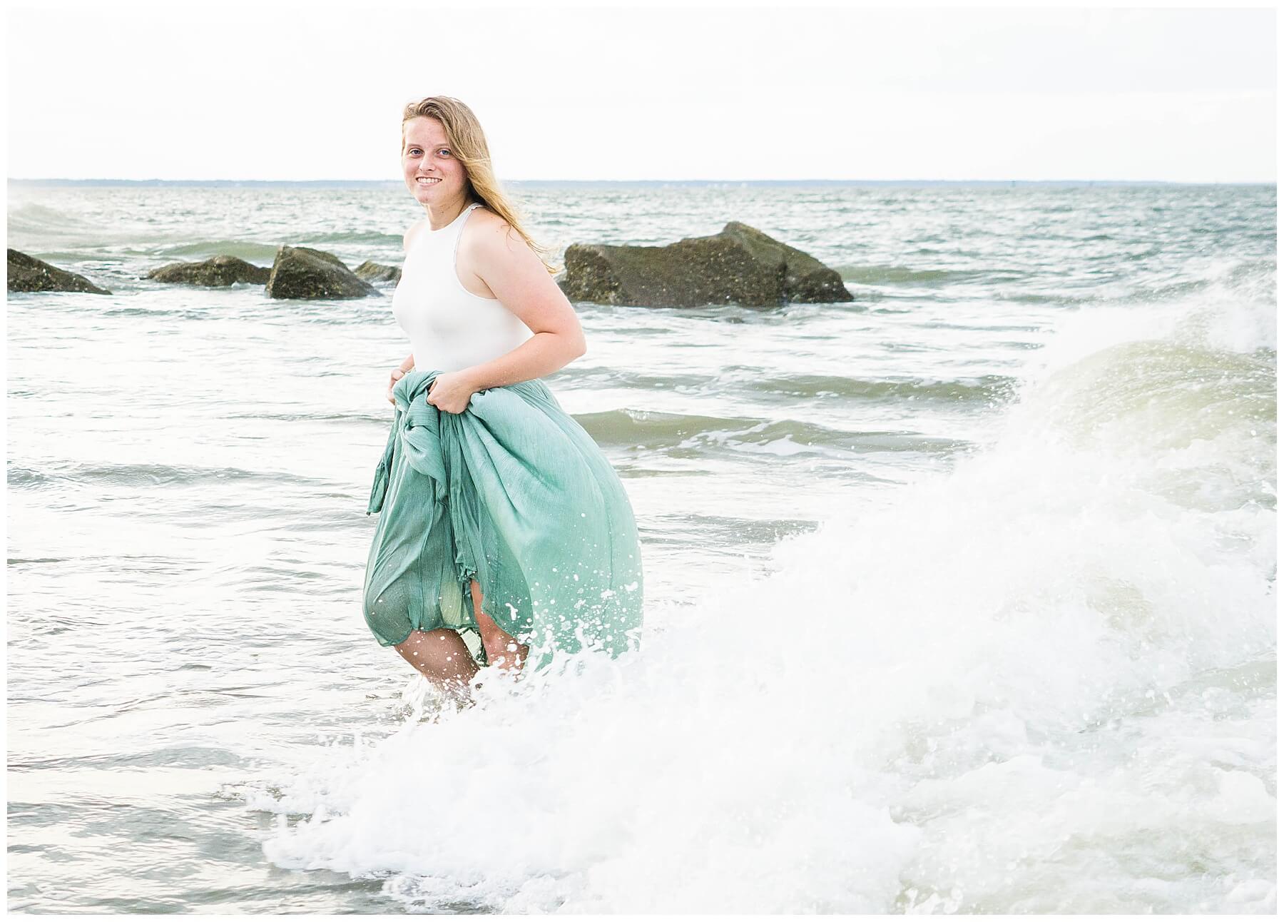 girl in long green skirt standing in waves