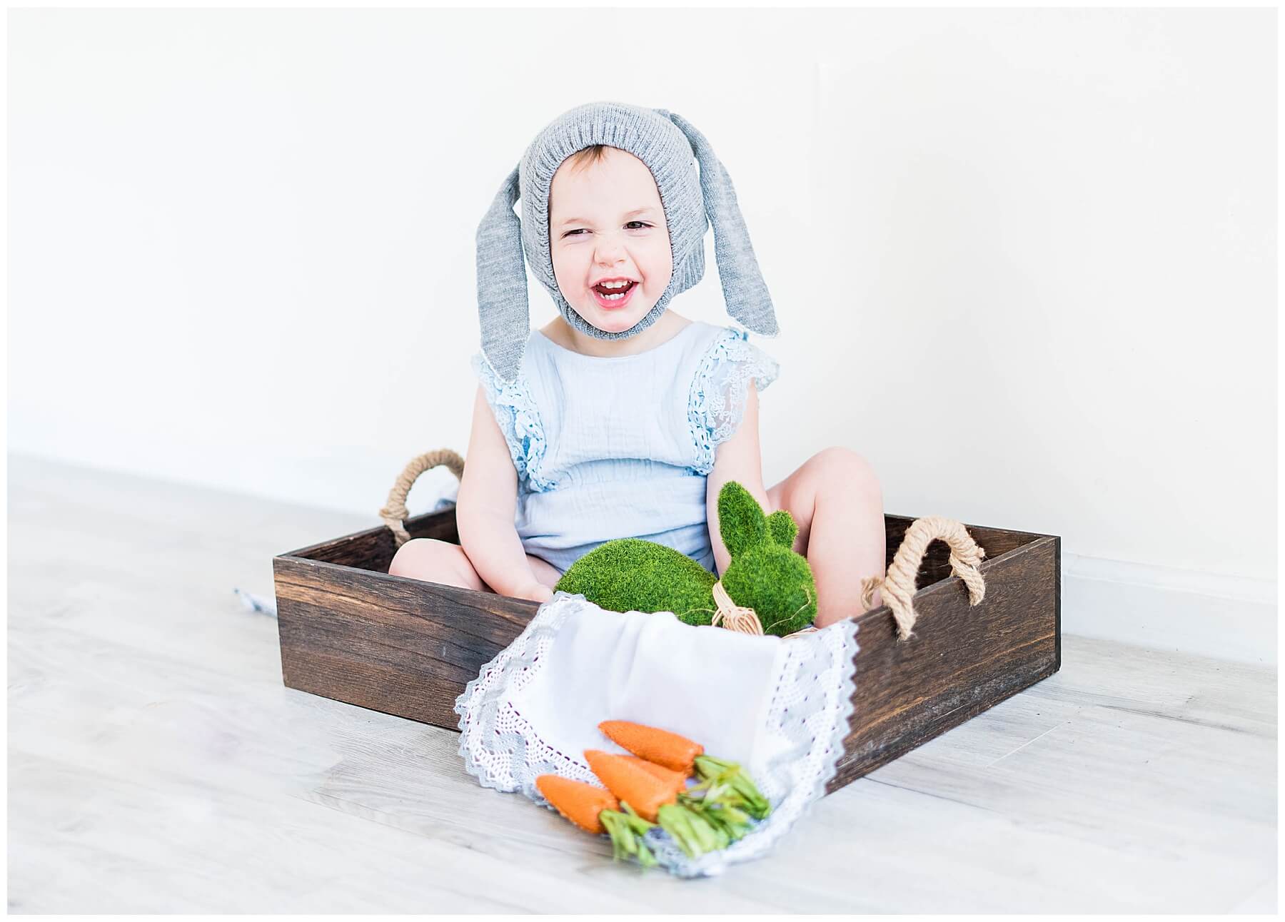 baby girl sitting in wooden box with easter decor