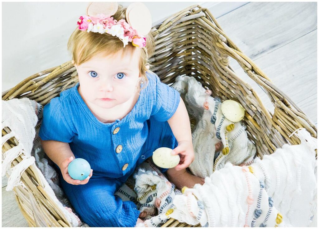 baby girl sitting in basket with easter decor
