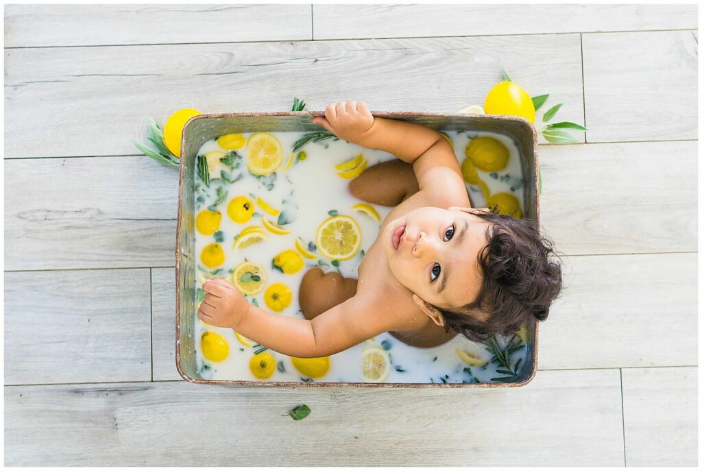 little boy sitting in a milk bath of lemons and herbs