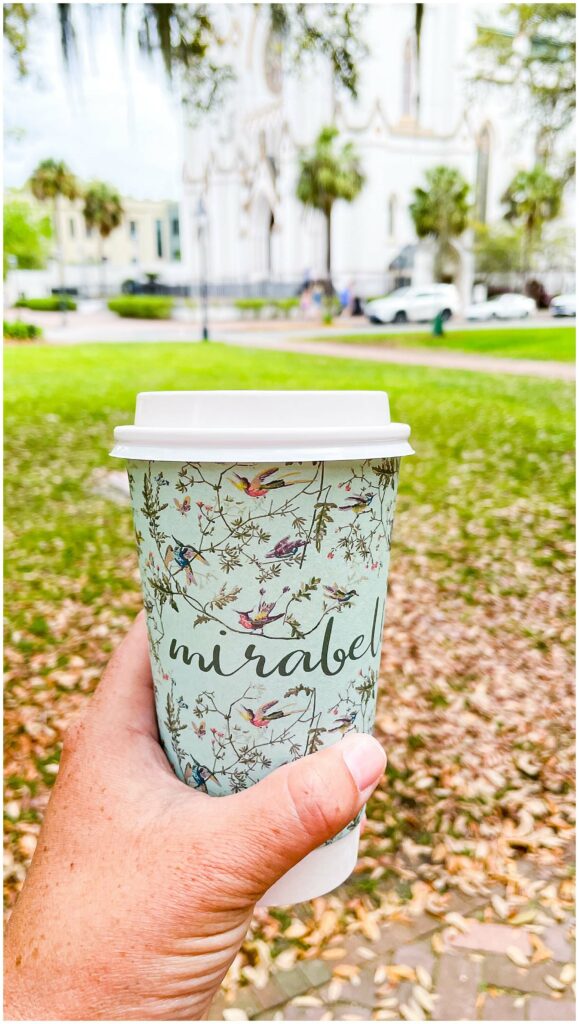 cup of coffee from Mirabelle Savannah in Lafayette Square with Cathedral of St. John the Baptist in the background