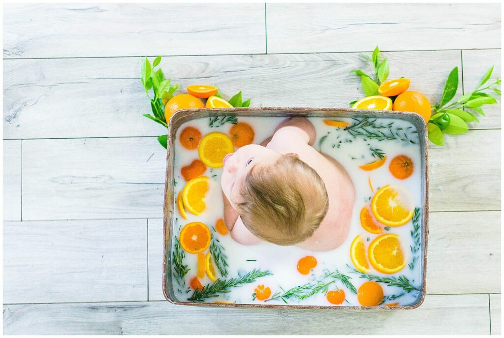 baby boy in milk bath of oranges and herbs
