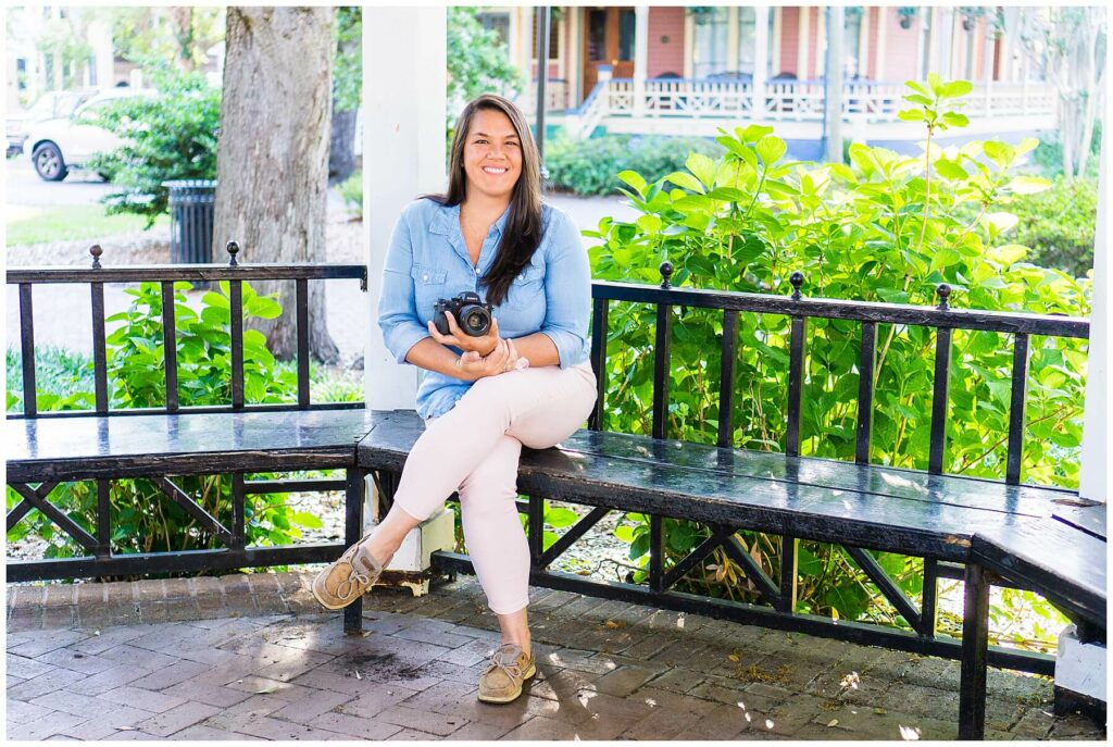 Savannah family photographer Jaden Giorgianni sits in the Whitefield Square gazebo holding a camera