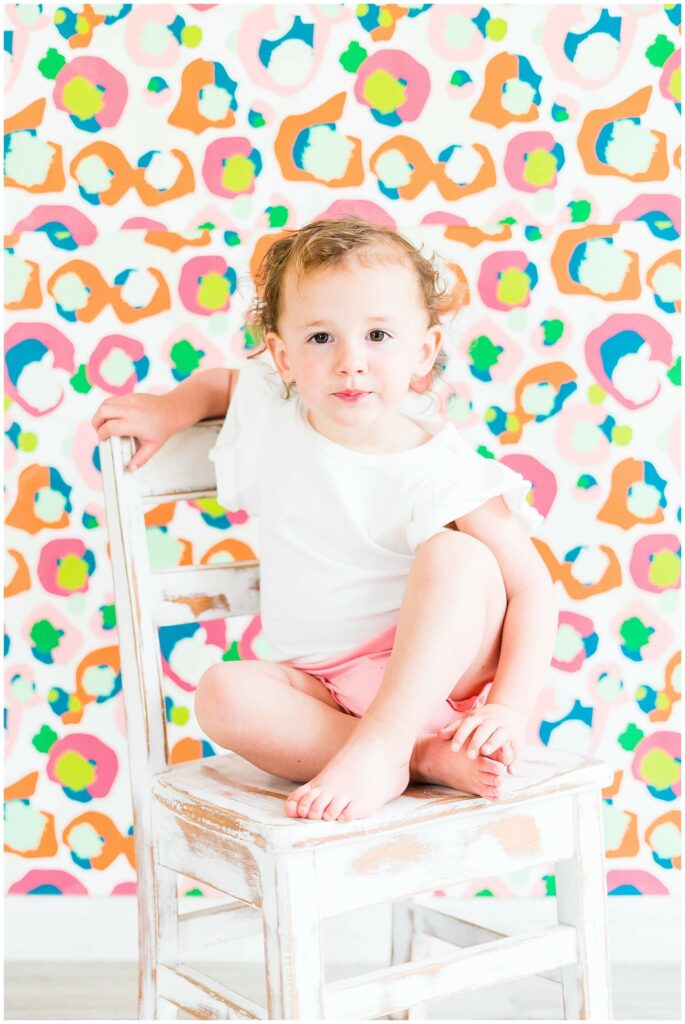 little girl sitting on a chair in front of Emily McCarthy spot cheetah patterned wall