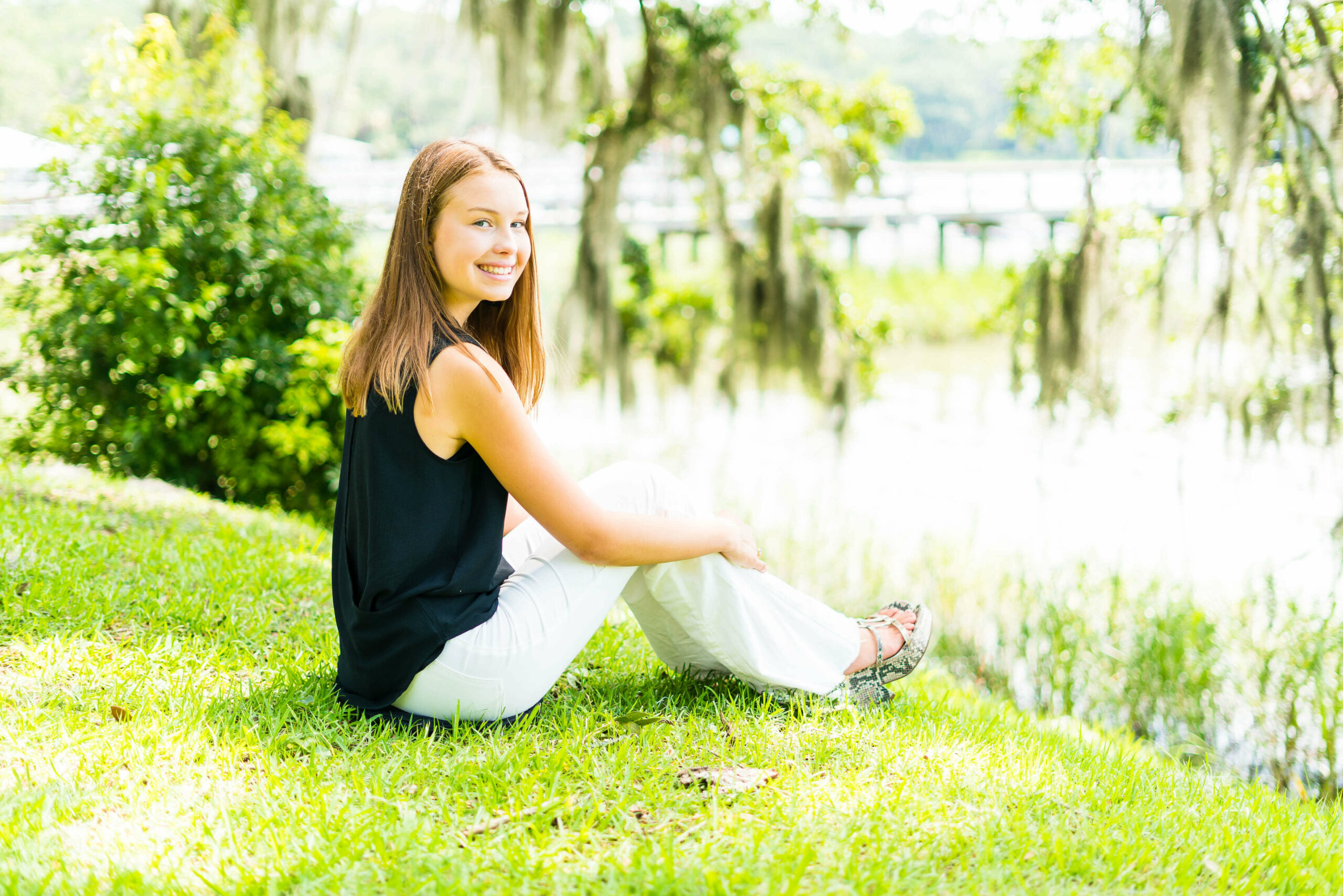 high school senior sitting on bluff bank overlooking water in savannah georgia