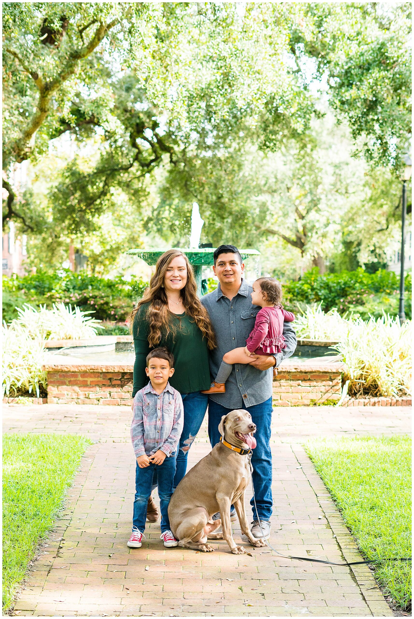 family of four with a dog standing in from of a fountain in downtown savannah's Columbia Square