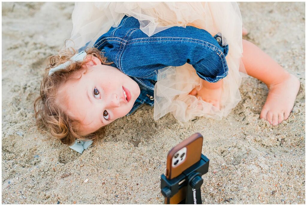 little girl laying on beach looking at iPhone