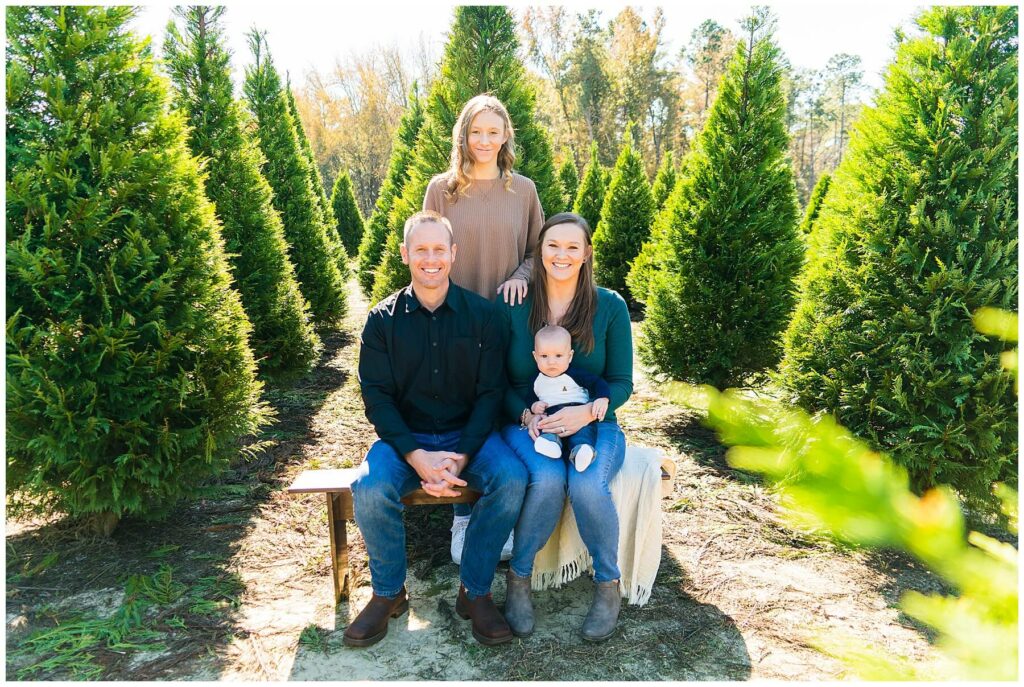 family of four taking photos at Christmas tree farm