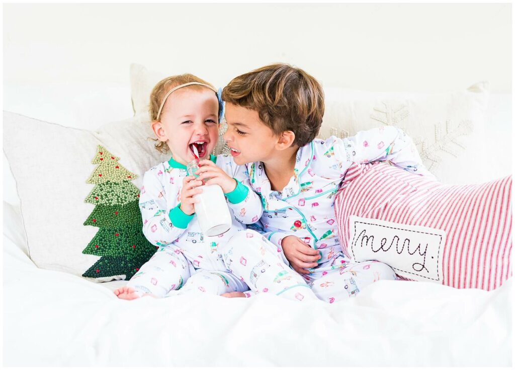 boy and girl in matching pajamas eating cookies and sipping milk in bed