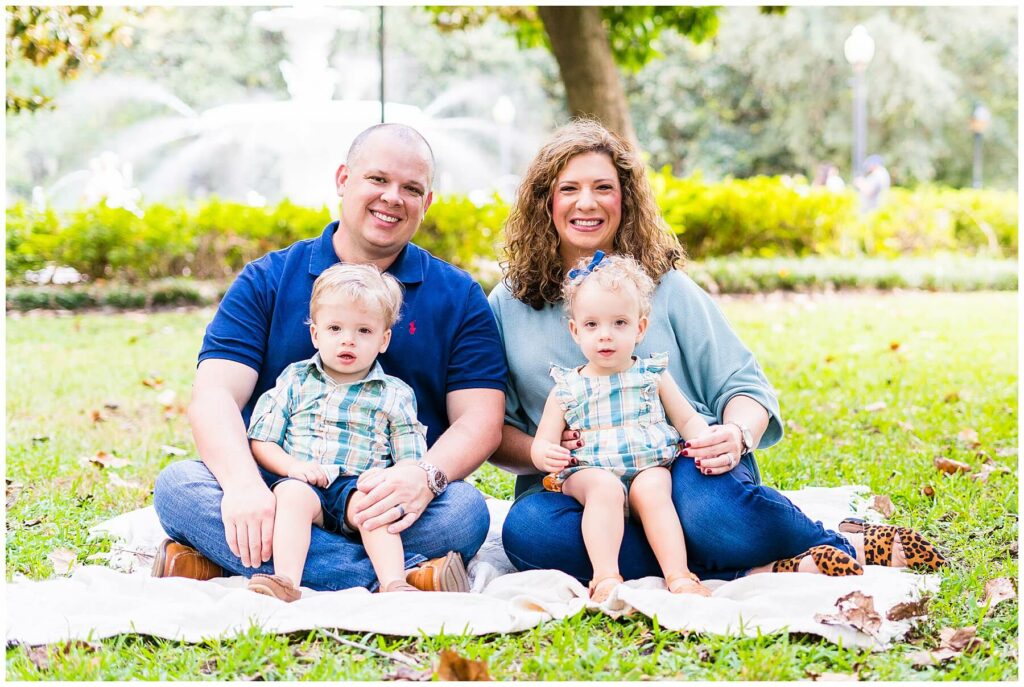 family of four smiling at the camera in Forsyth Park Downtown Savannah