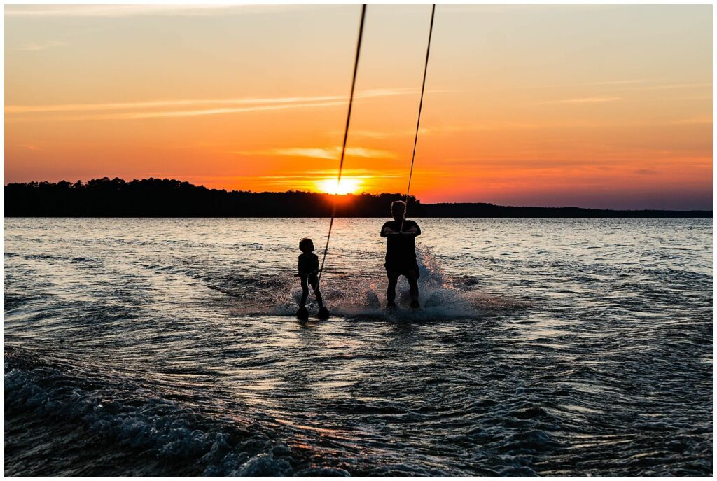 boy and man water-skiing with sun setting behind them