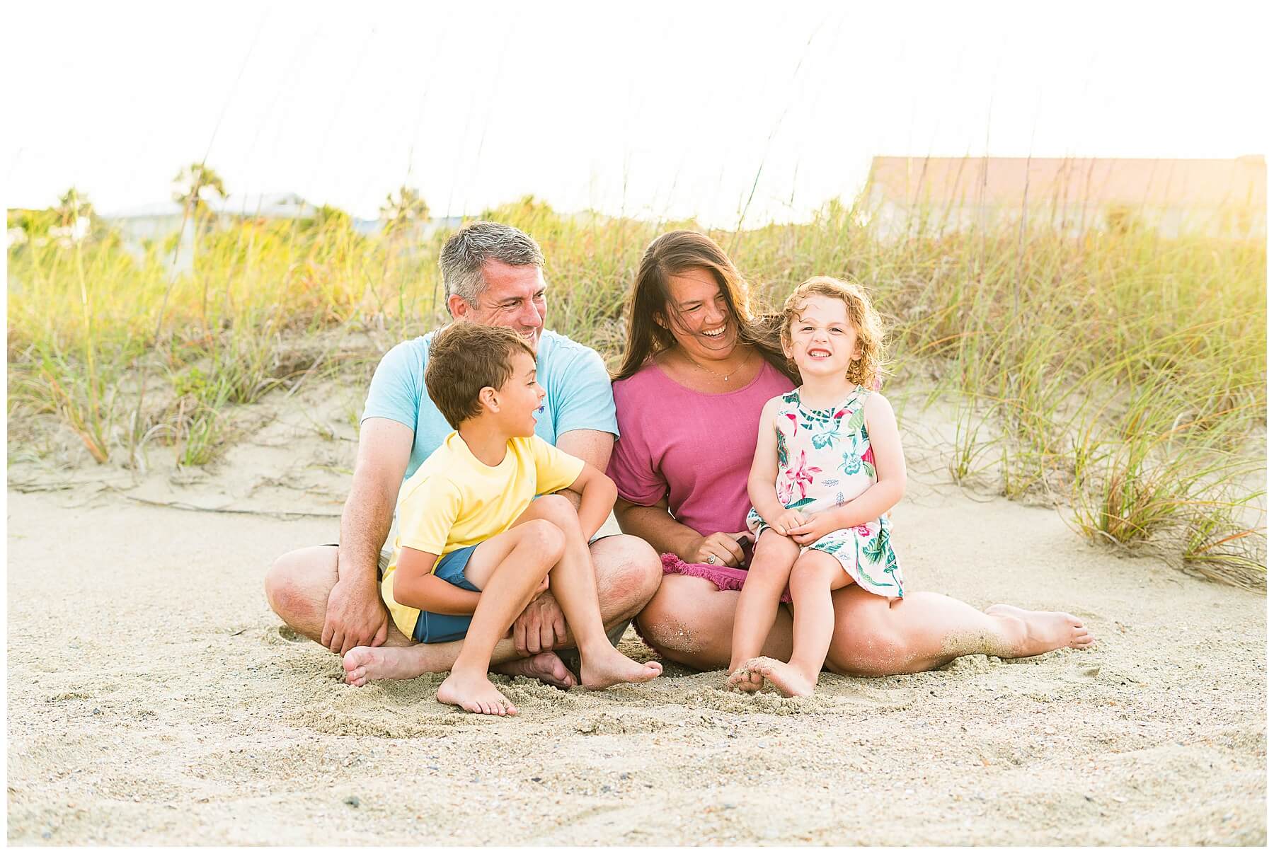 family of four sitting in the sand on Tybee Island for a sunset photoshoot