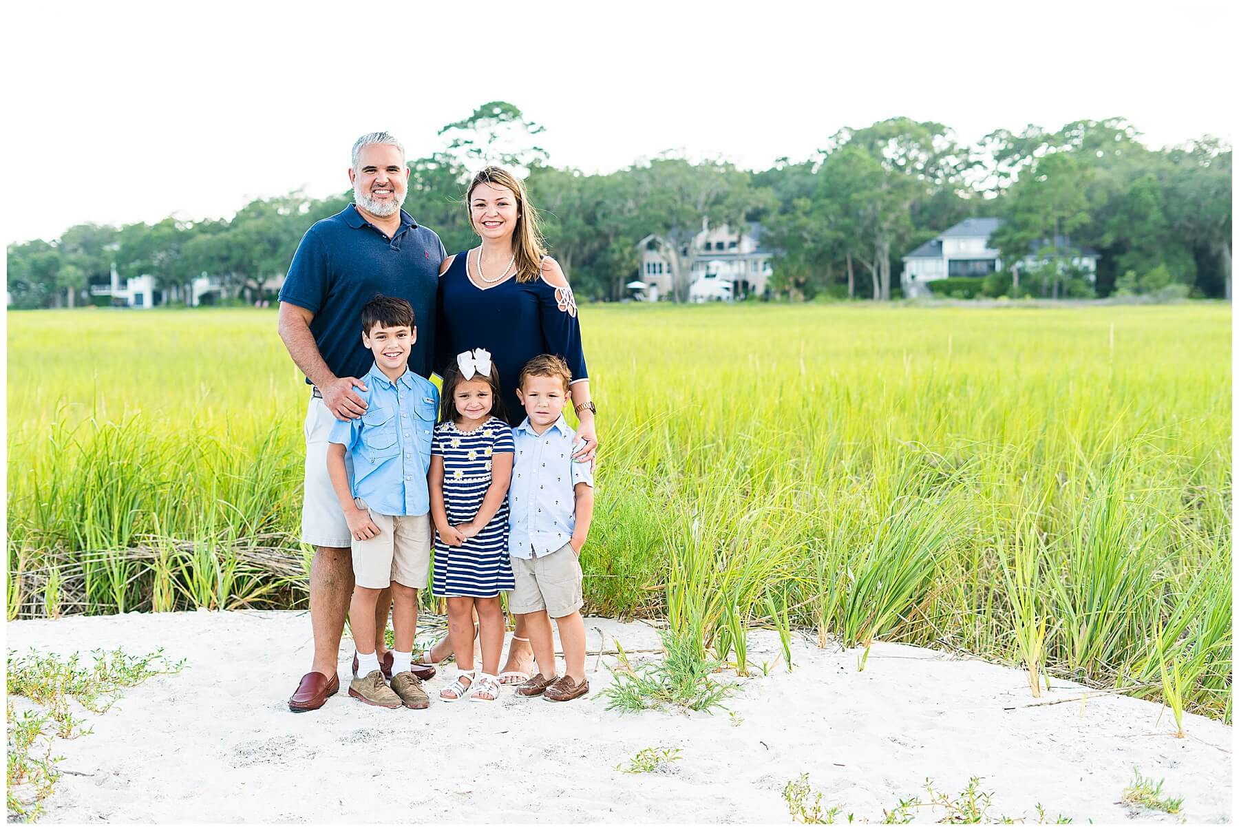 family of 5 standing in white sand with marsh in background for family photo in savannah Georgia