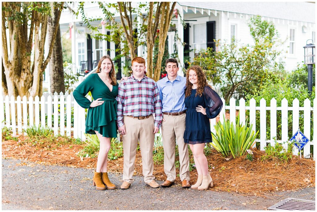 4 young adults standing together on Isle of Hope's Bluff Drive for family photos 