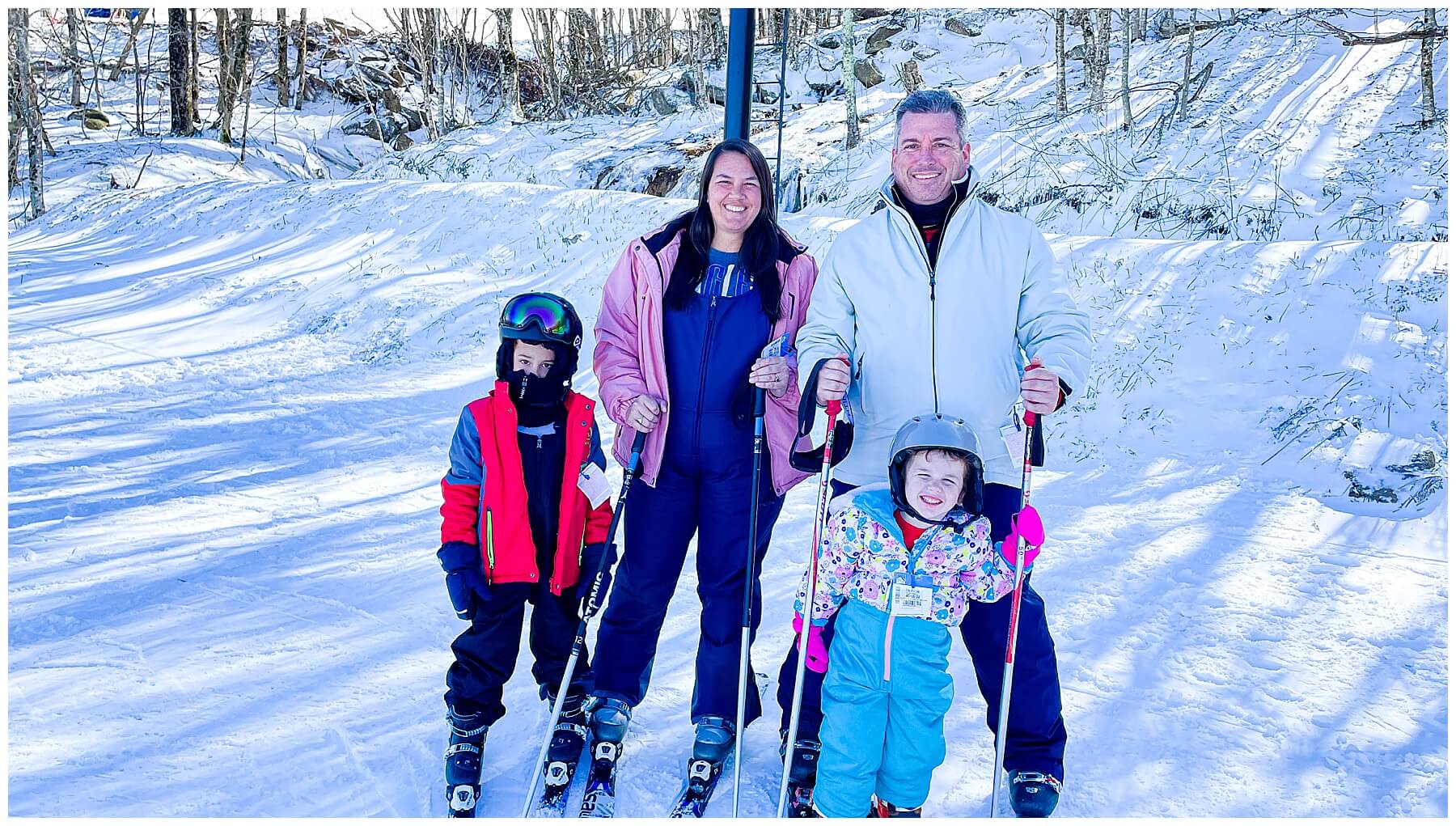 family of four standing in snow skis at the top of beech mountain