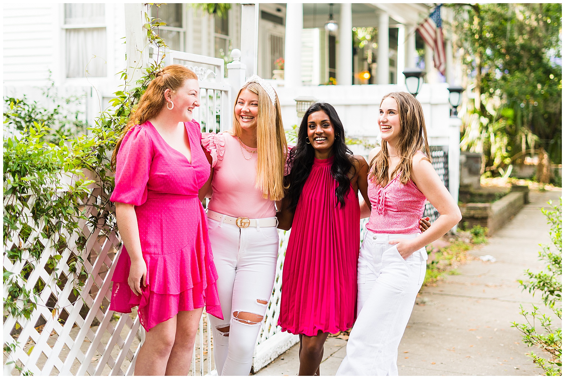 group of four high school seniors wearing pink and white laughing in a group photo