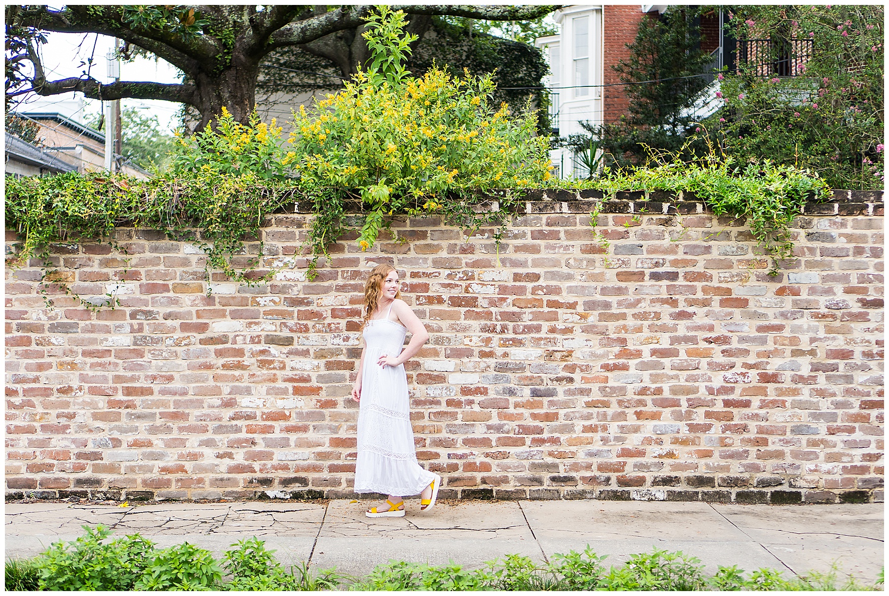 high school senior girl in white dress standing in front of a brick wall in downtown savannah, Georgia