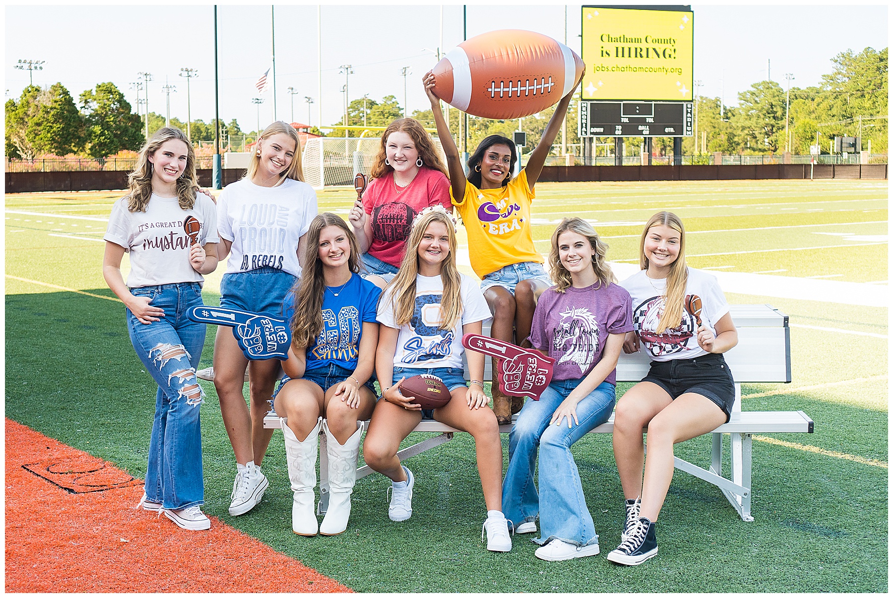 high school girls sitting around a football bench modeling t-shirts in Savannah's Memorial Stadium