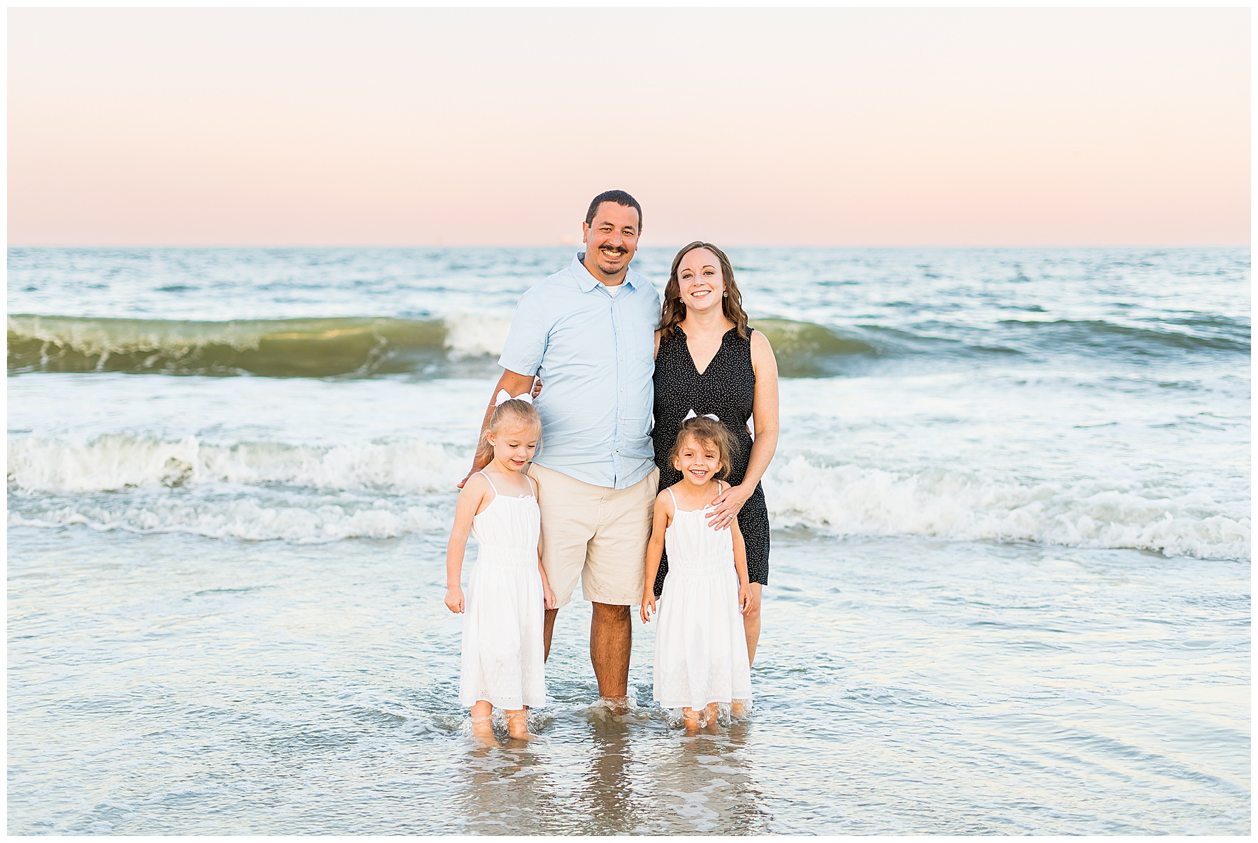 family of four standing in the ocean at sunset on Tybee Island