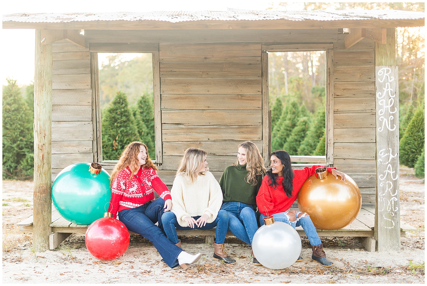high school senior girls sitting in a shed with large holiday ornaments at a tree farm near Savannah, Georgia