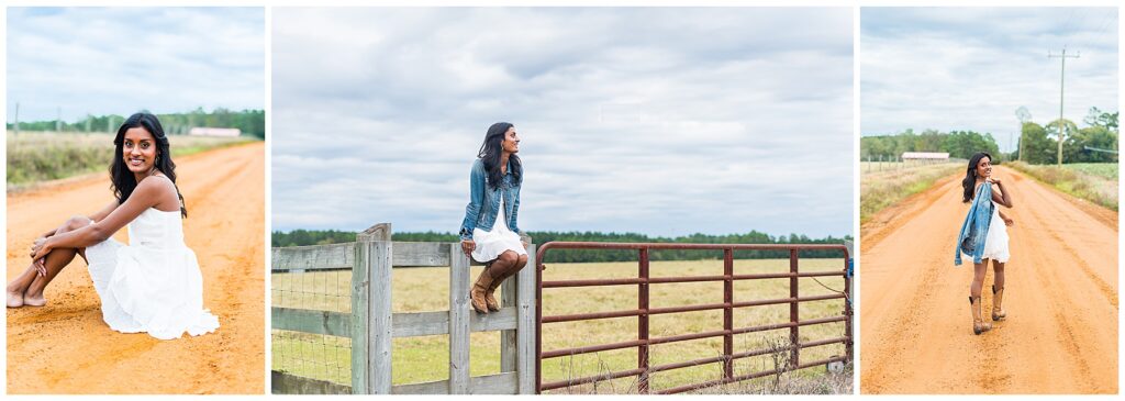 high school senior wearing a white dress and denim jacket having photos taken on a red dirt road