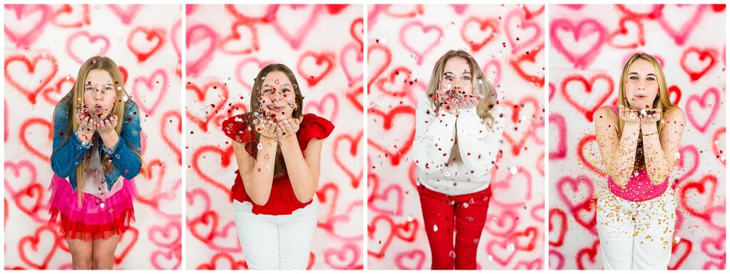 4 high school girls blowing glitter at the camera in front of a heart backdrop