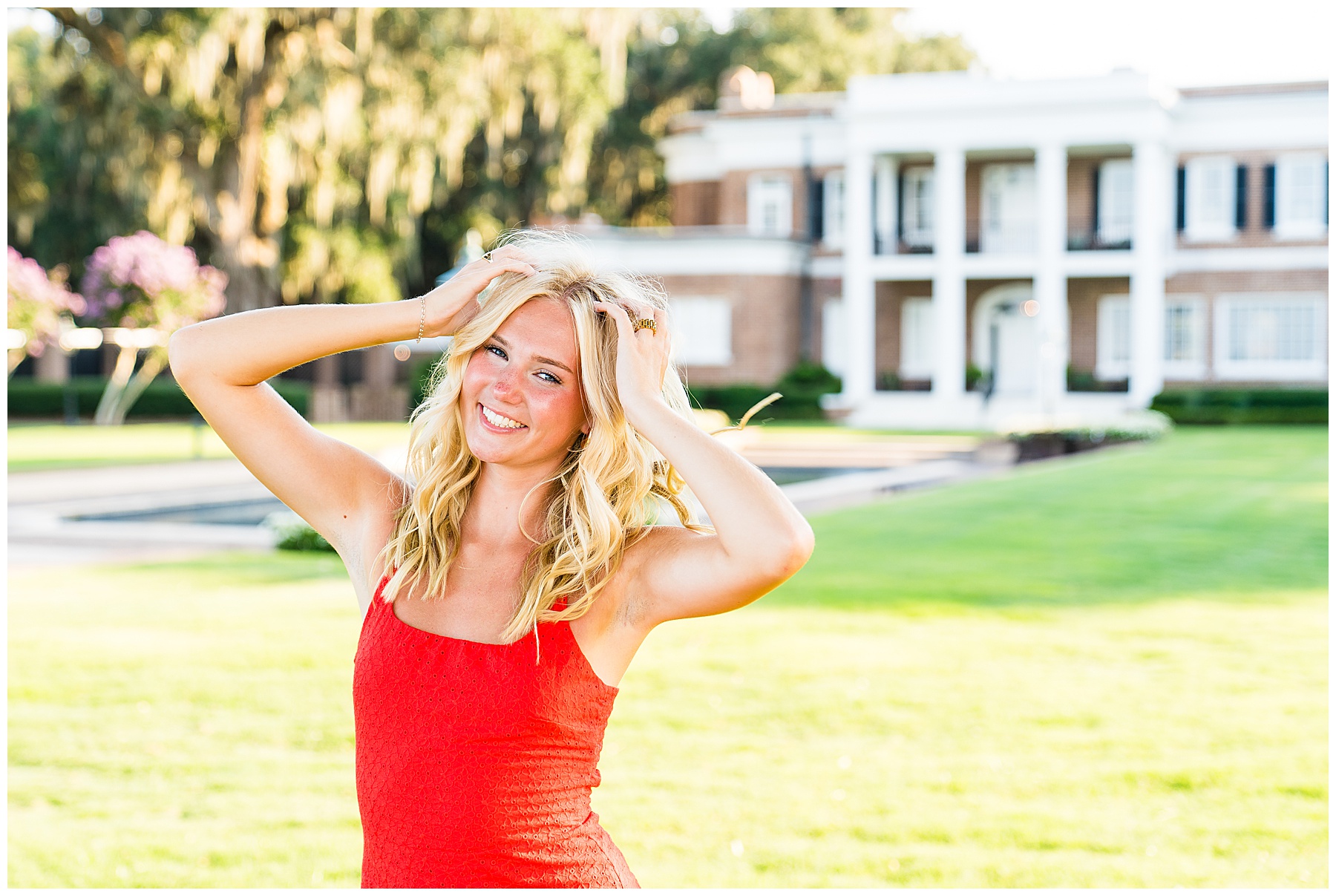 photo of a blonde girl wearing a red dress in front of a stately home