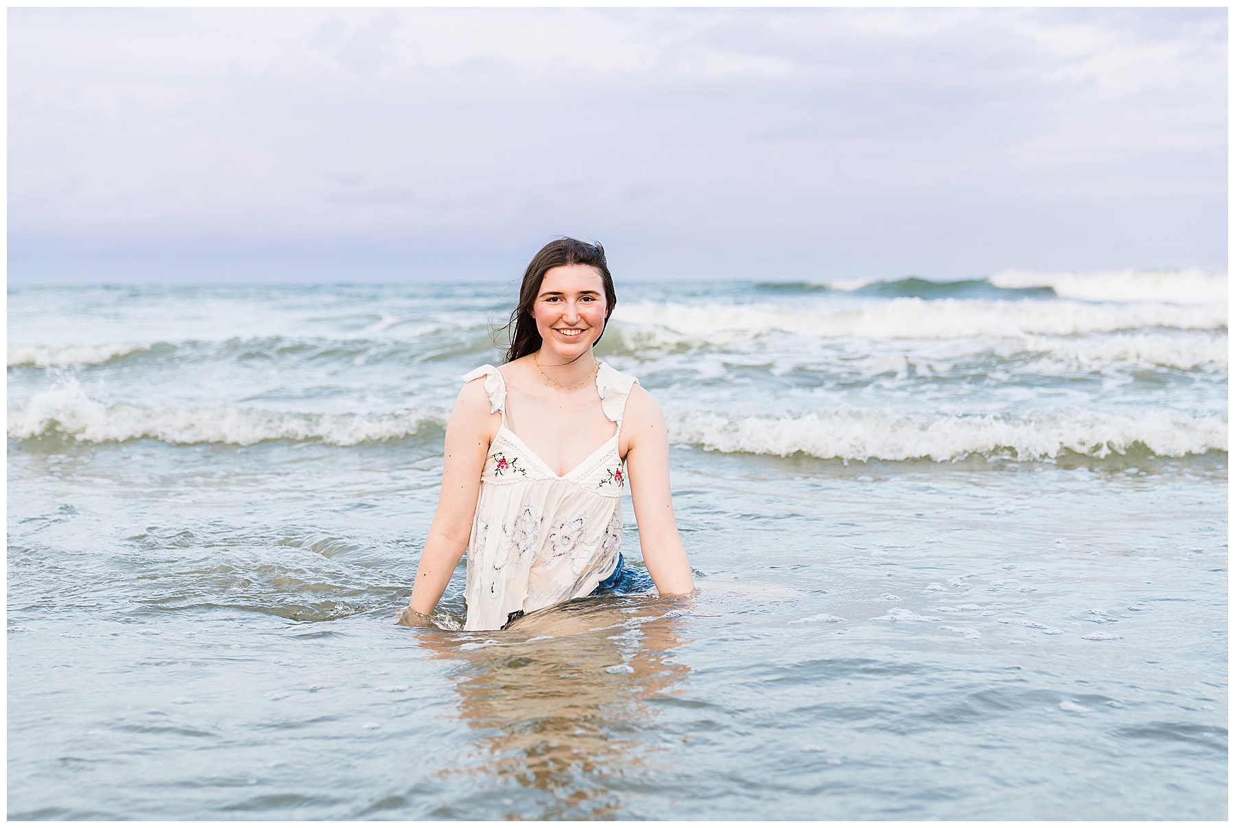 photo of high school senior having her photo taken wearing a cream top with jean shorts on Tybee Island on sunset.