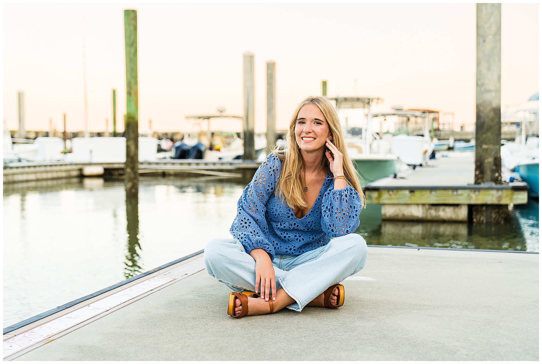 photo of a high school senior wearing a blue long sleeve top and blue jeans at the landings harbor marina having her senior pictures taken