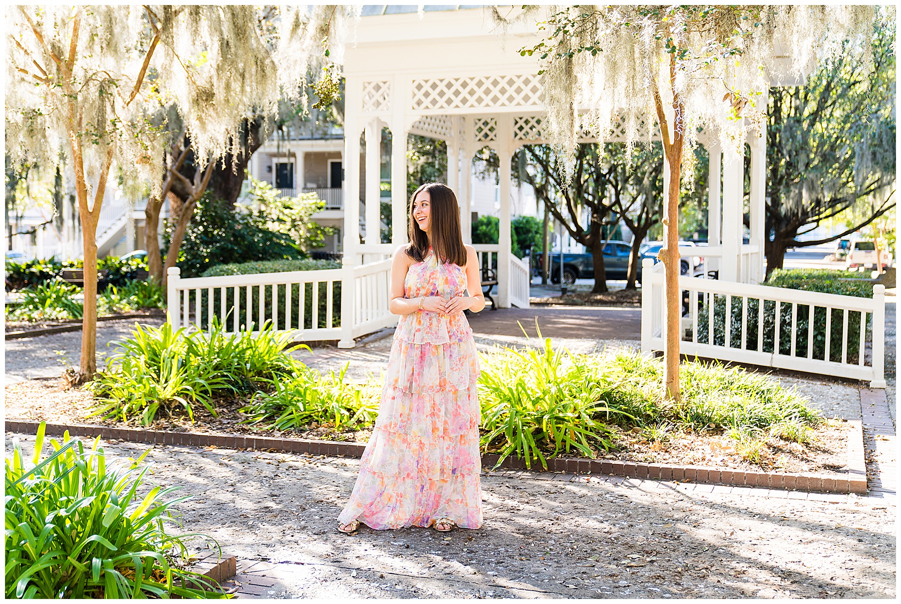 photo of a high school senior girl wearing a pastel floral maxi dress standing in front of a gazebo in Savannah Georgia