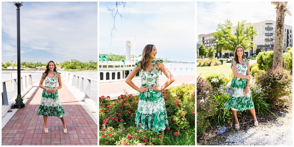 This collage features a young woman posing in three different outdoor settings, all in Savannah, GA. She is wearing the same green and white floral sundress with tie straps and cream heels in each photo, creating a cohesive, summery look. Left Image: She stands confidently on a brick-paved pier or walkway by the river, framed by a tall lamppost and cable-railed fencing. The open sky and distant greenery create a serene coastal vibe. Middle Image: She’s laughing joyfully while standing among vibrant red flowers, with a classic paddlewheel riverboat in the background. This adds a lively, iconic Savannah touch, evoking a playful, carefree mood. Right Image: She smiles warmly beside tropical landscaping, including blooming purple flowers and a palm tree. Modern buildings and a green park are visible behind her, balancing natural charm with urban style. Overall, the set conveys a joyful, confident energy—ideal for senior portraits—celebrating both personality and place in a fresh, vibrant way.